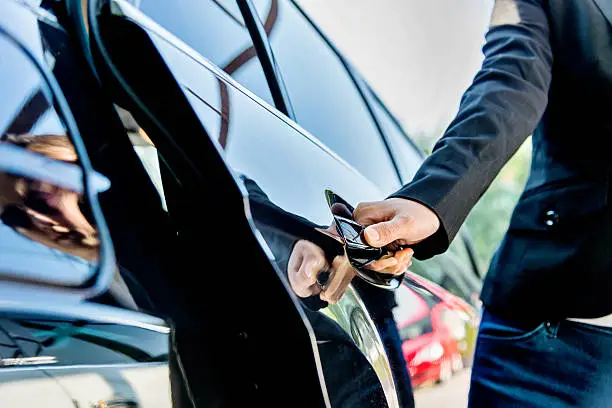 a chauffeur open door of a limo for business man who book an executive car service for business meeting